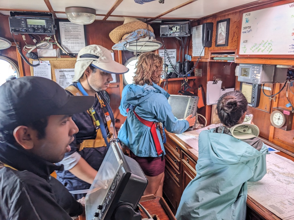 group of people looking at radar on a ship