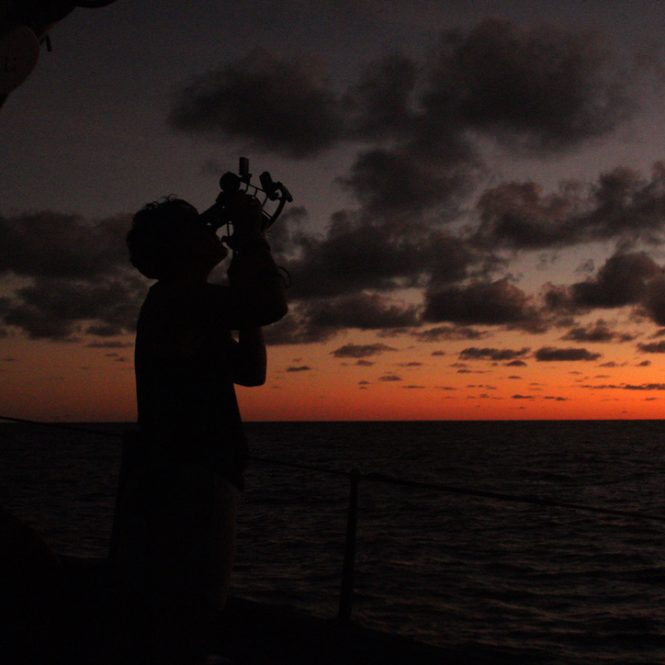 silhouette of a woman using a sextant at sunset